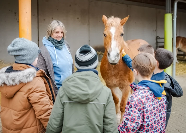 Vier Kinder mit einem Pferd und einer Betreuerin